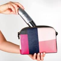 Hand putting SkinMedica Total Defense + Repair sunscreen into purse pouch