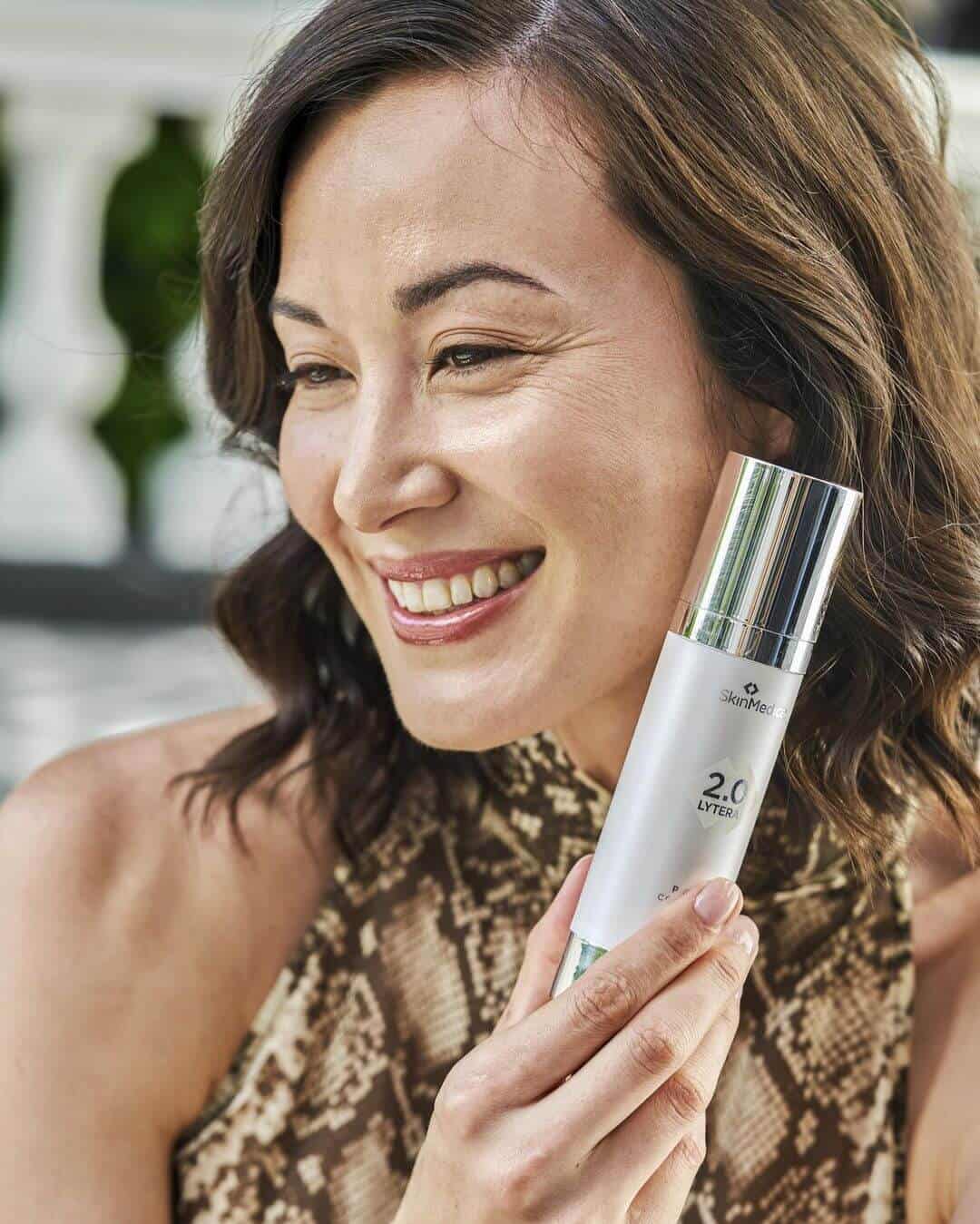 Woman holding SkinMedica Lytera 2.0 next to face - showing bottle size - available in Canada