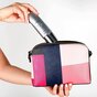 Hand putting SkinMedica Total Defense + Repair sunscreen into purse pouch