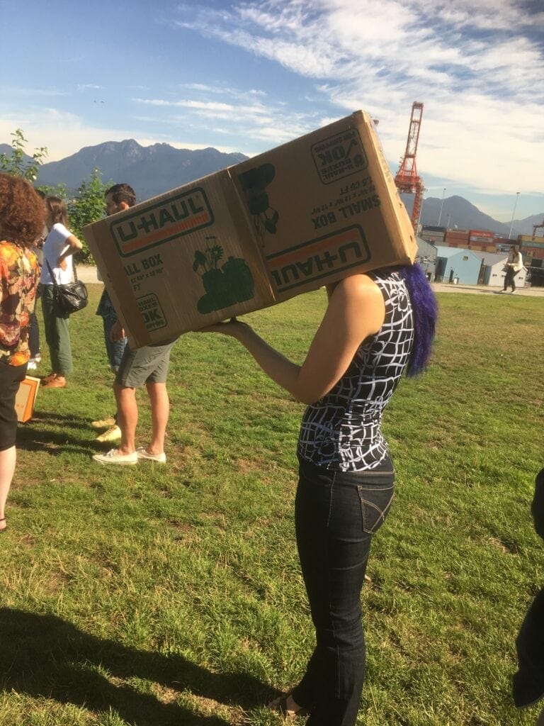 Photo of OXD staff Deborah with a box on her head as part of team games