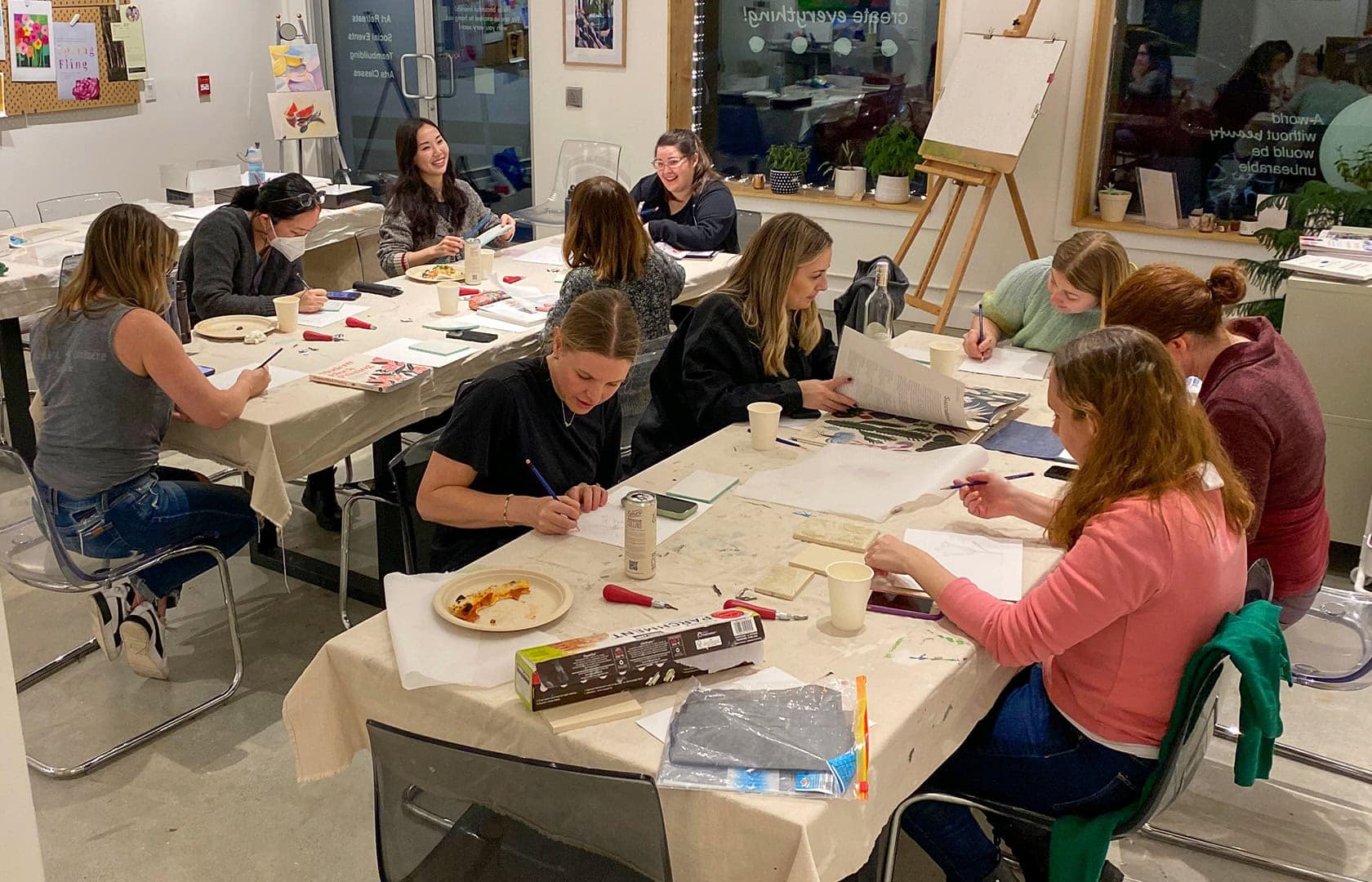 Photo of staff sitting at two tables working on the hand sketches
