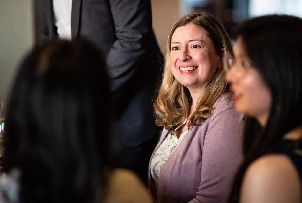 Photo of Sara smiling listening to people talking