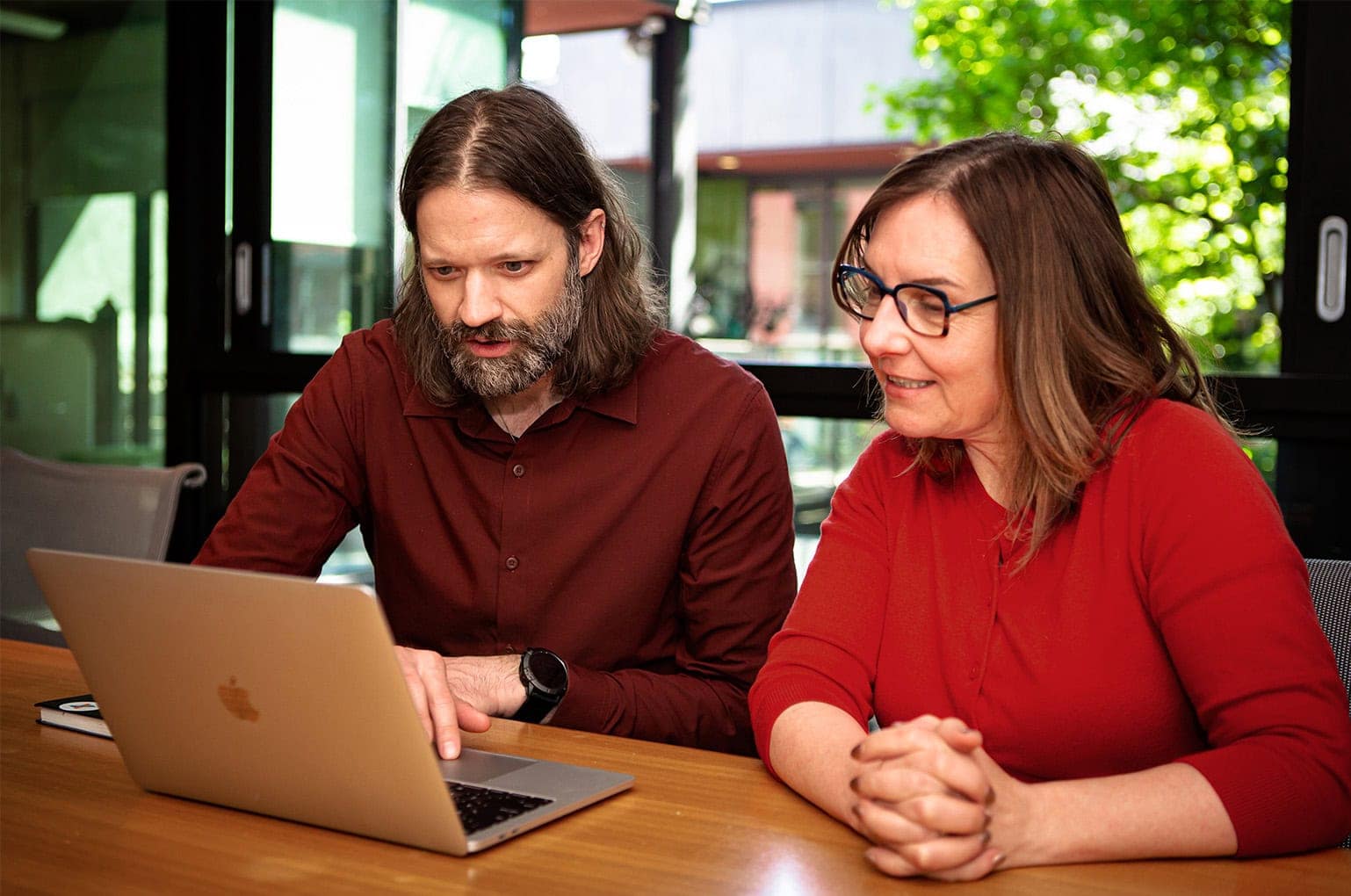 Two people sitting at a table looking at a laptop