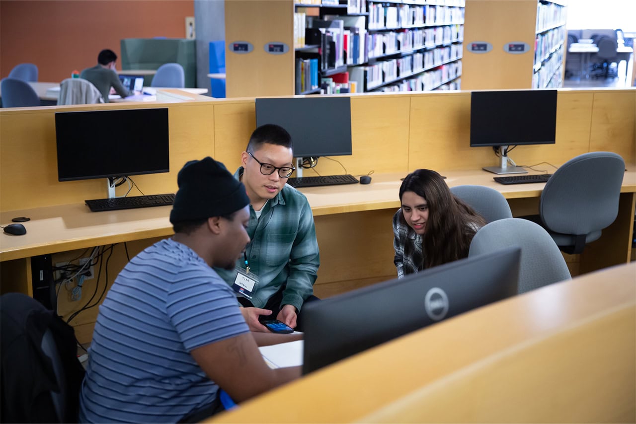 Three participants collaborating in a library.