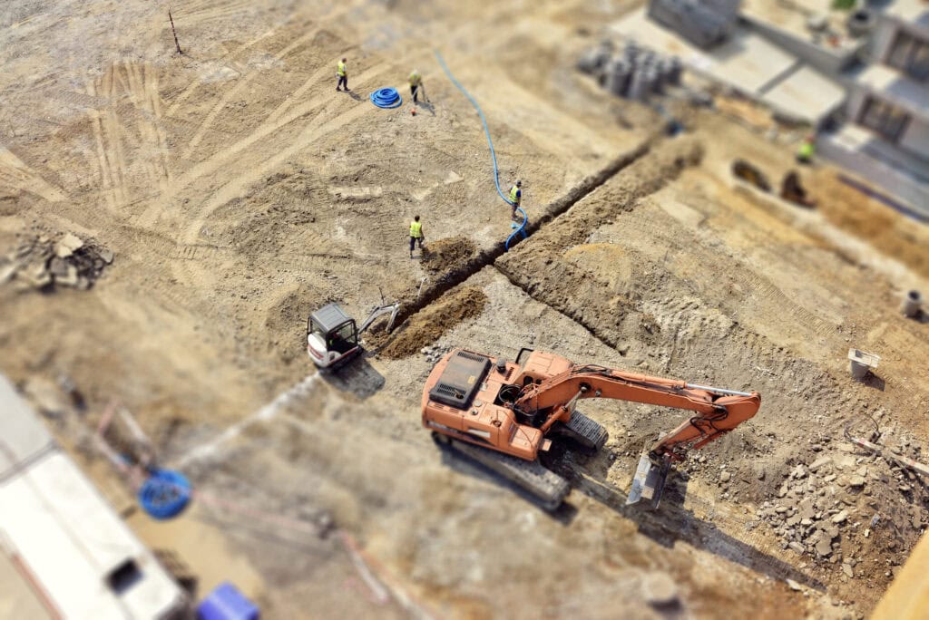 Workers, Engineers digging in ground, sewer system, street, tilt-shift, above land site preparation